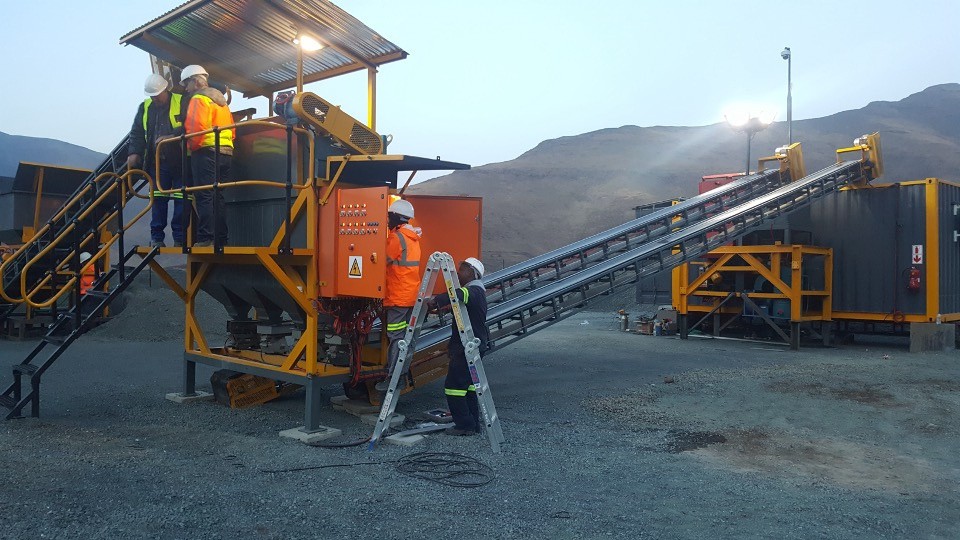 Grey processing modules and yellow conveyor on a mine site